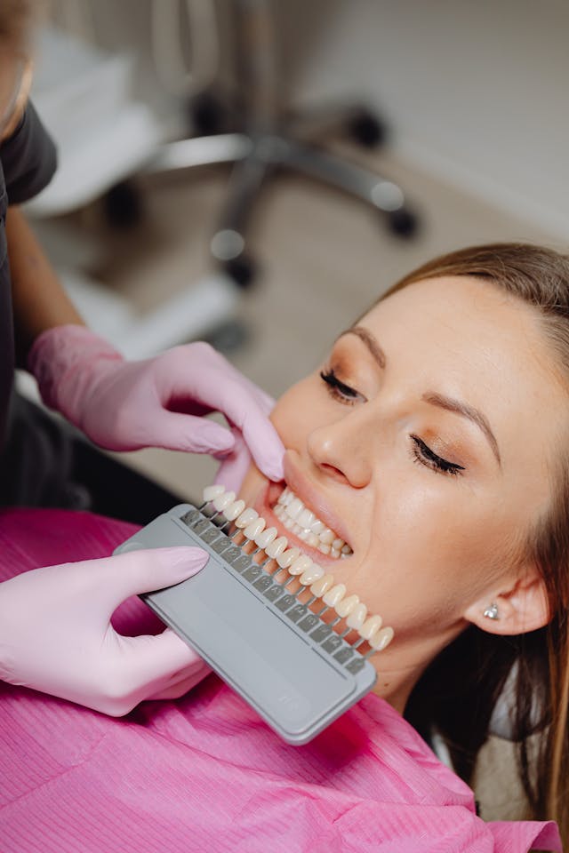 A dentist compares sample tooth colours to a patient's teeth