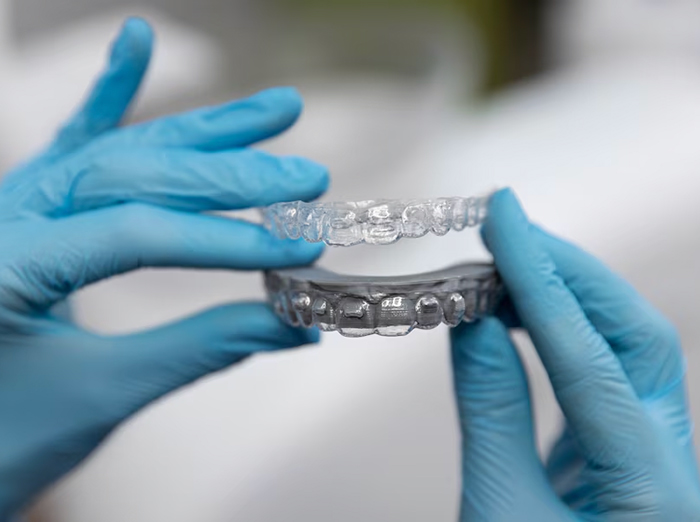 Gloved handing holding an aligner
