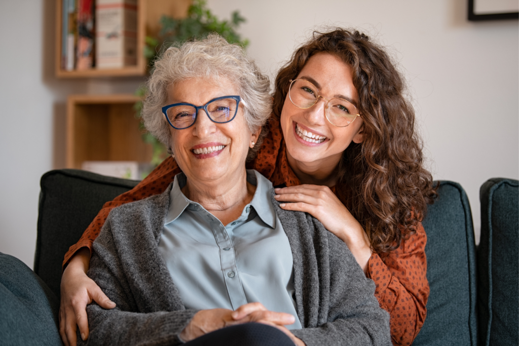 A senior mother and her adult daughter hugging on a couch