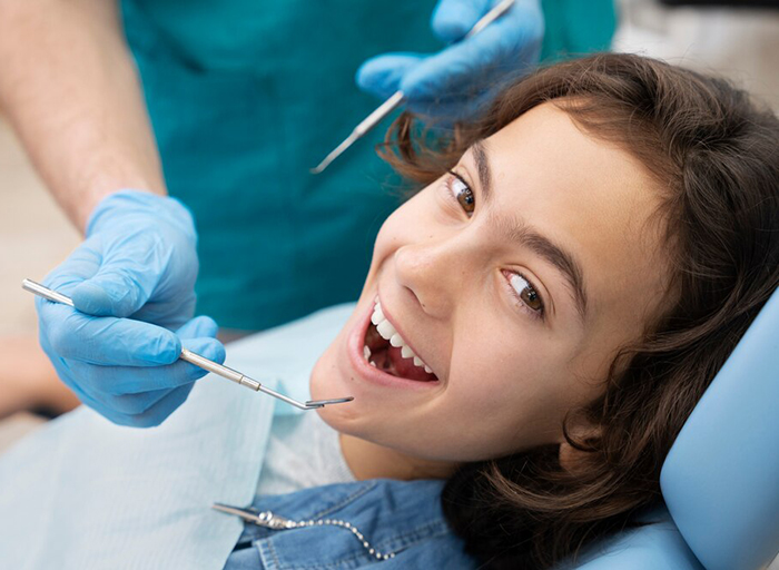 A child smiling while having their mouth examined by a dentist