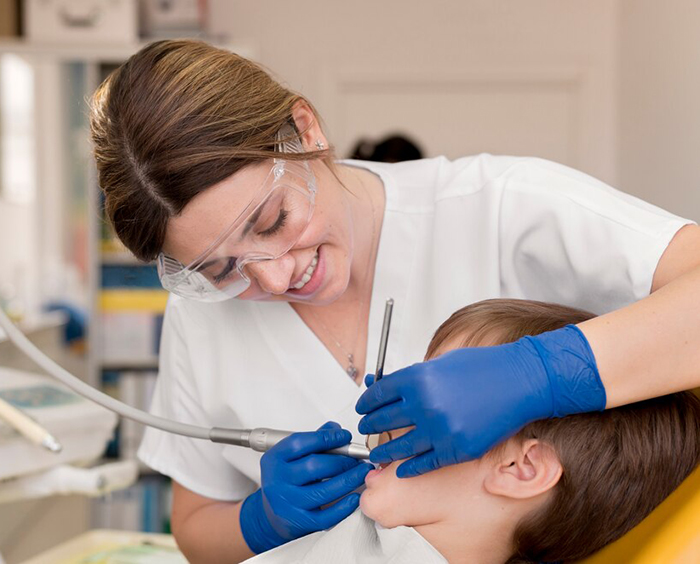 A dentist working with tools in a young patient's mouth